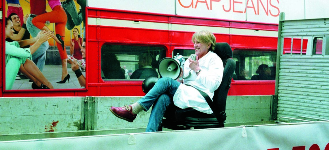  Woman sat on a chair with a megaphone in front of a bus