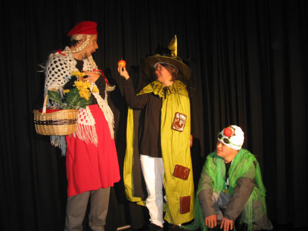 Three performers on a stage, each dressed in a fancy dress outfit.
