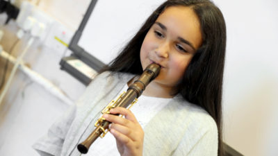 A girl playing a one-handed Recorder