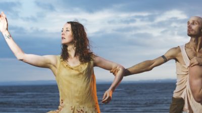 A woman and two men with the sea and sky in the background.