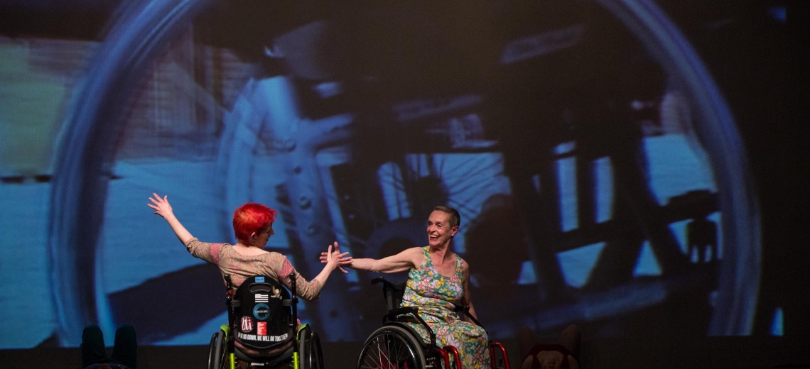 Two women in wheelchairs on stage. 