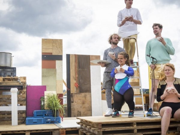 5 performers sitting on a stack of pallets