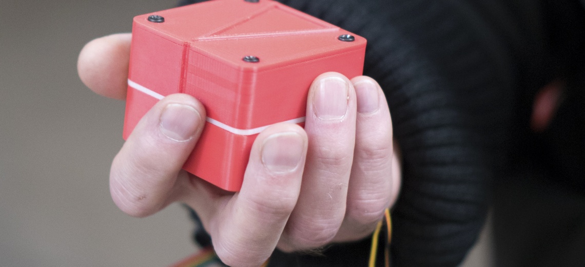 A hand holding a red plastic box. 