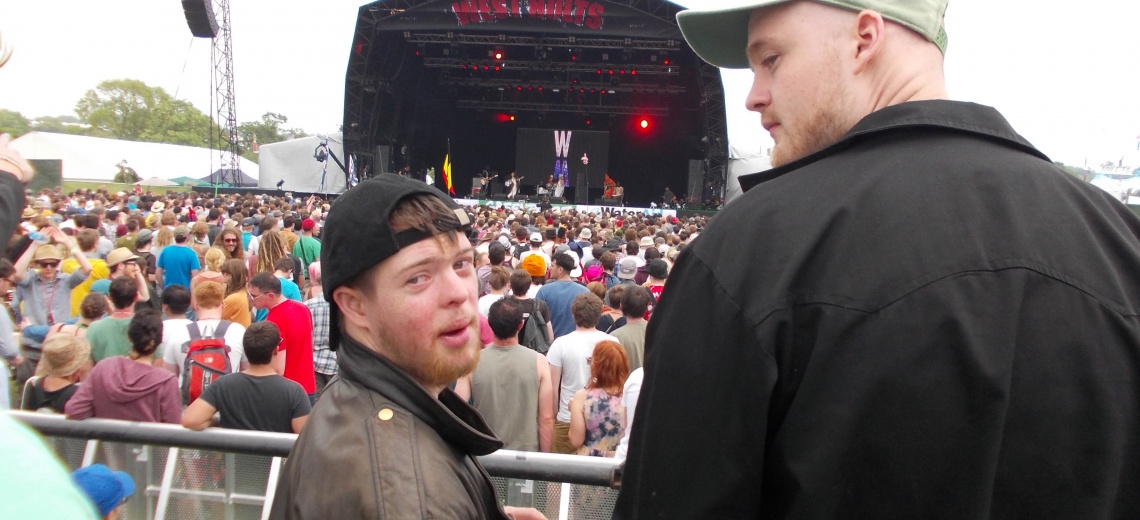 Learning disabled man standing at the back of a big crowd at Glastonbury