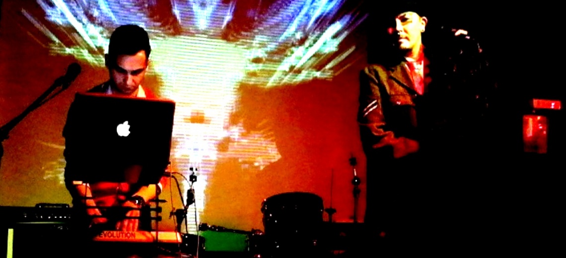 Two men on a stage with a projection as a backdrop. 