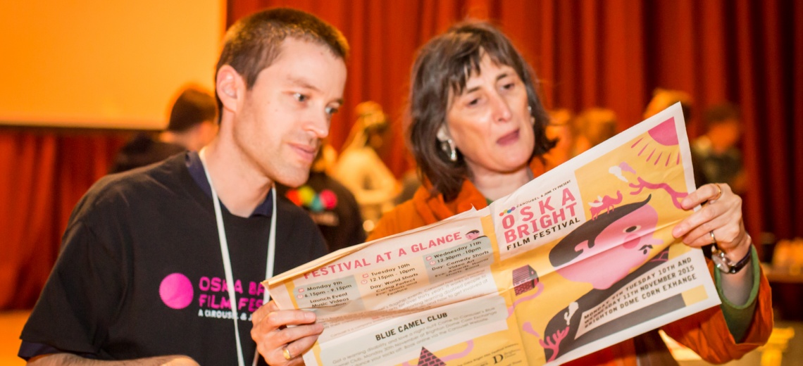 A man and a woman looking intently at a newspaper