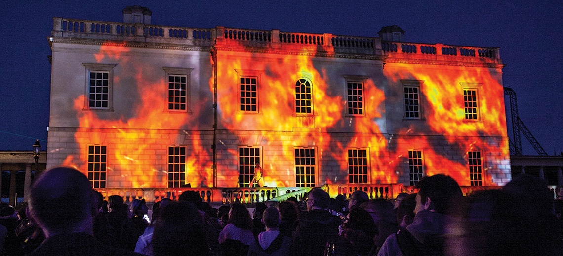 Light projection of fire onto a large stately building. 