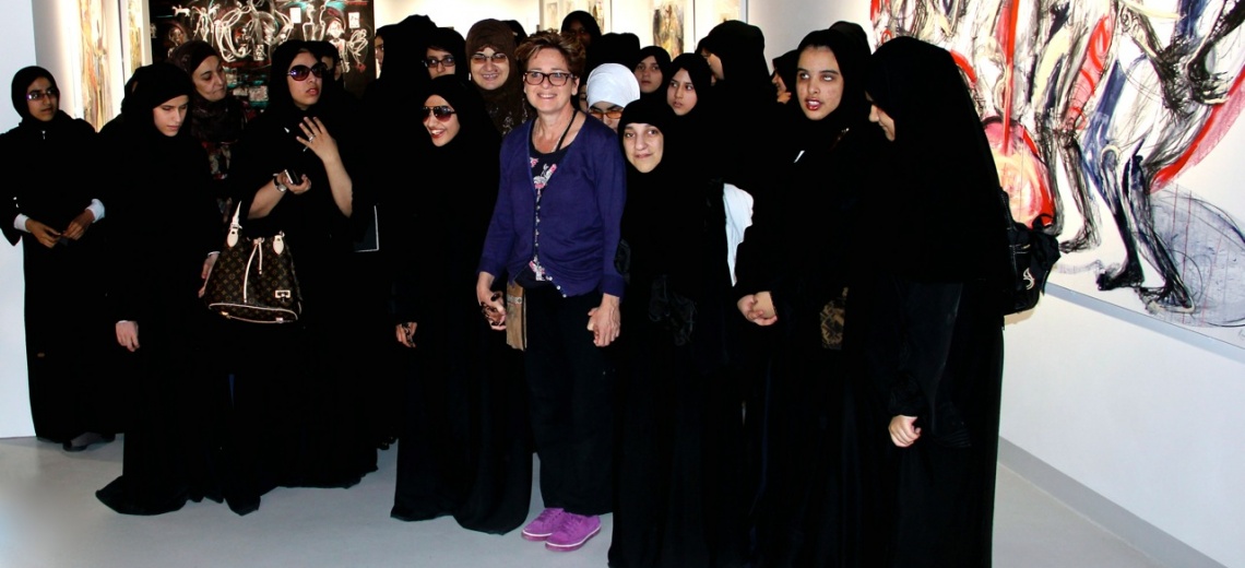 A woman in western clothing standing amongst a group of women in black Islamic dress. 