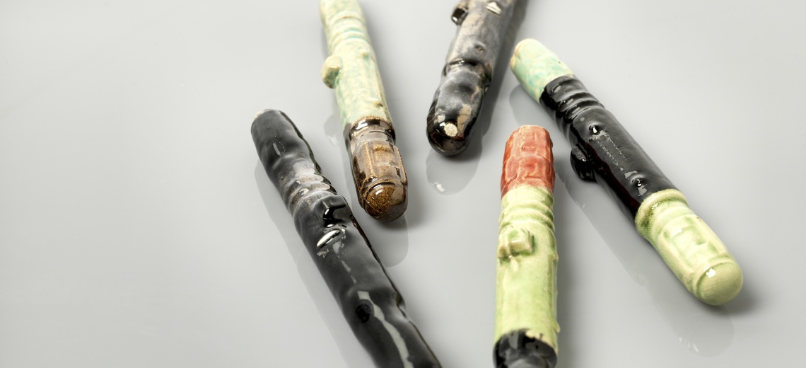 Five ceramic pen shaped items. 