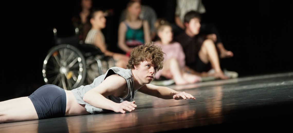 Performer lying on his front on a stage