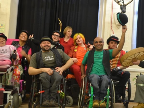 A group of performers in wheelchairs, smiling.
