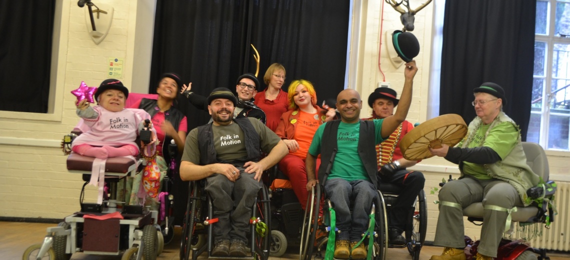 A group of performers in wheelchairs, smiling.