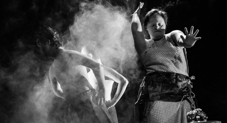 Three dancers on a stage with smoke rising from the background. 