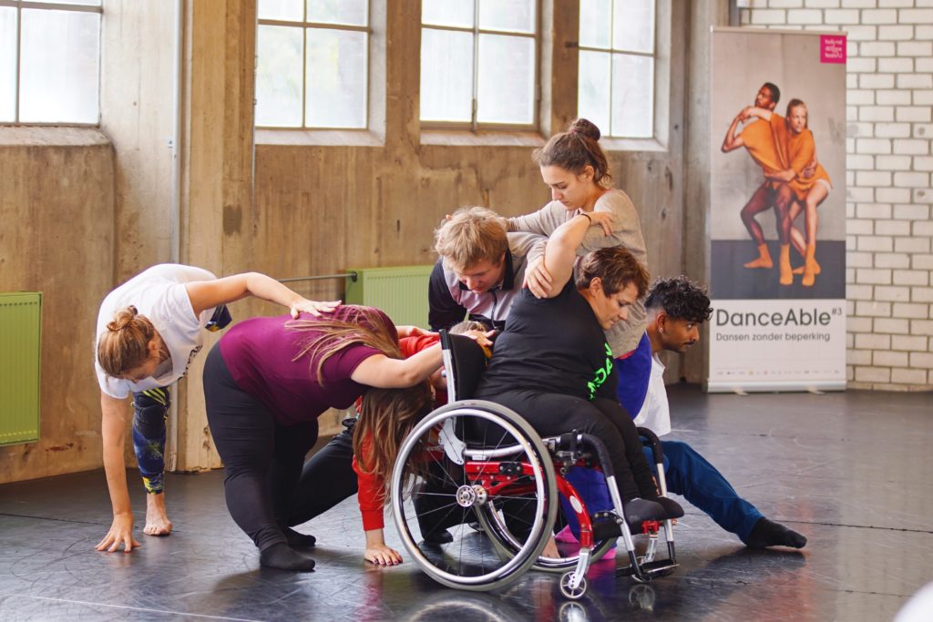 Dancers create a complex group structure reaching forward and backwards together