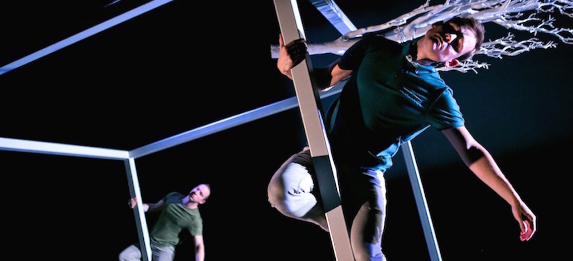 Two man hanging from a metal cube frame. 