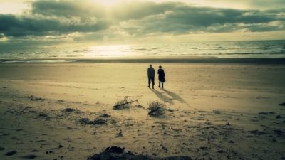 Screen grab showing two people walking on a beach