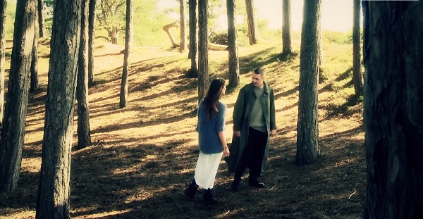 Miranda and Caliban face each other in the woods