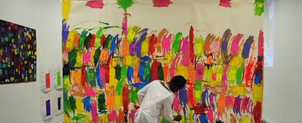 Photograph of a someone painting a large-scale colourful abstract piece