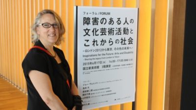 Photograph of Jo Verrent stnading next to a sign at a conference in Japan.