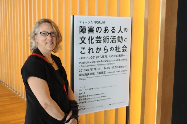 Photograph of Jo Verrent stnading next to a sign at a conference in Japan.