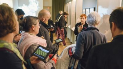 A group of people using Stagetext-enabled devices to look around an exhibition