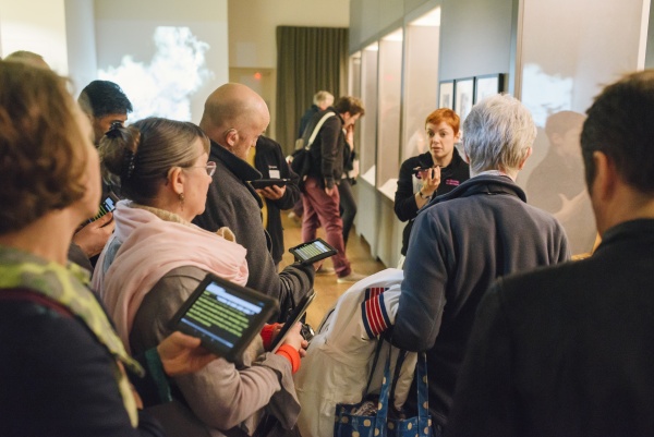 A group of people using Stagetext-enabled devices to look around an exhibition