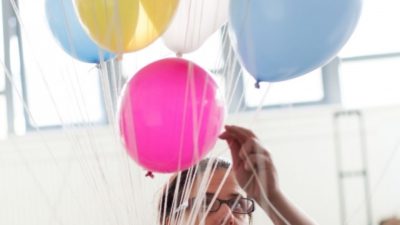 Noemi Lakmaier holding a bunch of colourful helium filled balloons