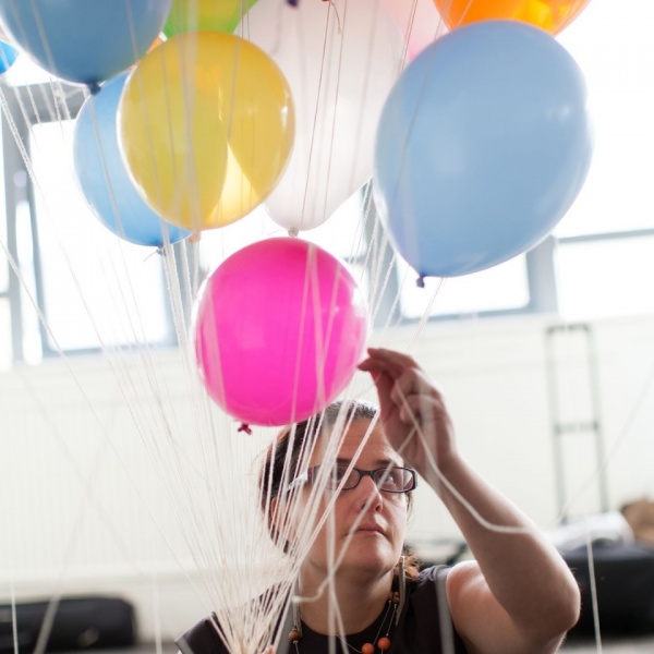 Noemi Lakmaier holding a bunch of colourful helium filled balloons