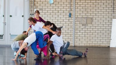 An international gathering of artists create a complicated group structure by intertwining their bodies in a dance studio.