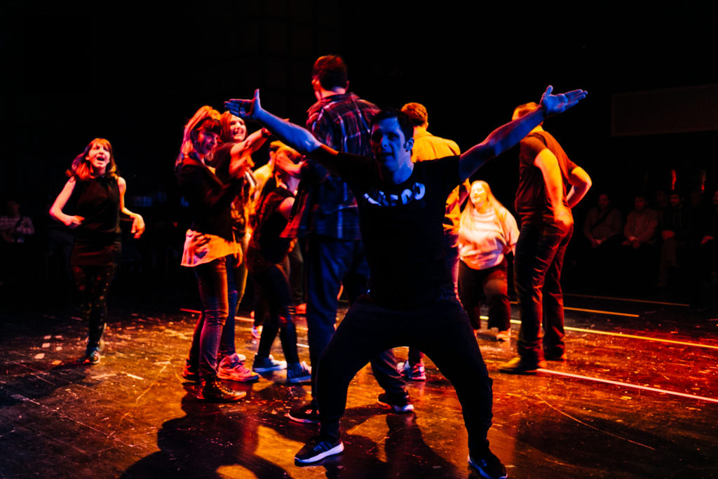 Group of performers dance around wildly