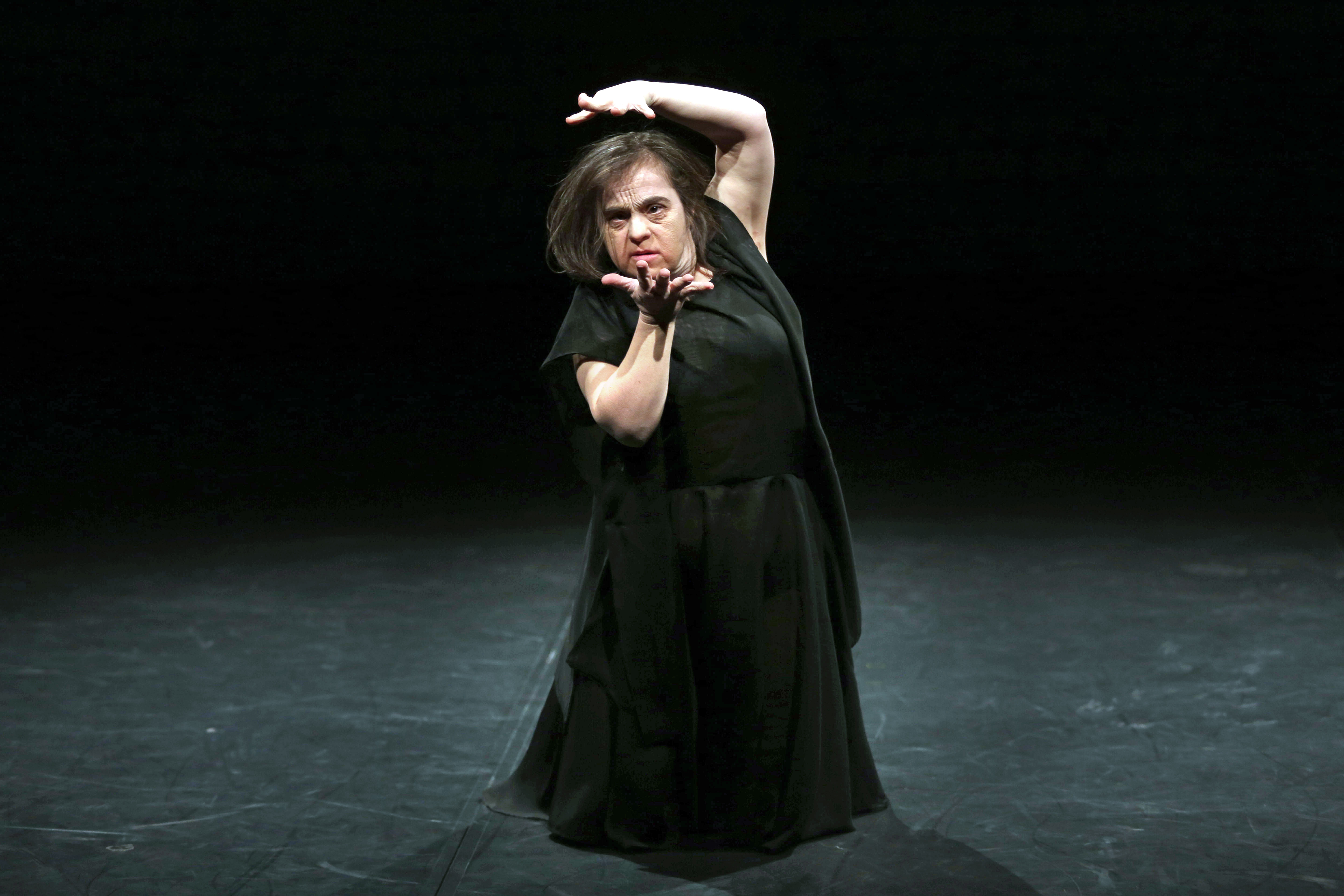 Learning disabled female performer dressed all in black gestures with hands