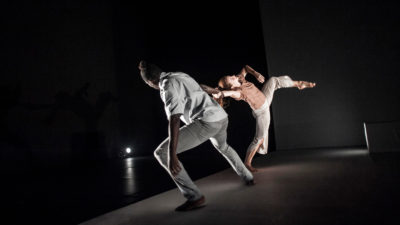 Black male and white female dancer holding each other by the hand and leaning backwards