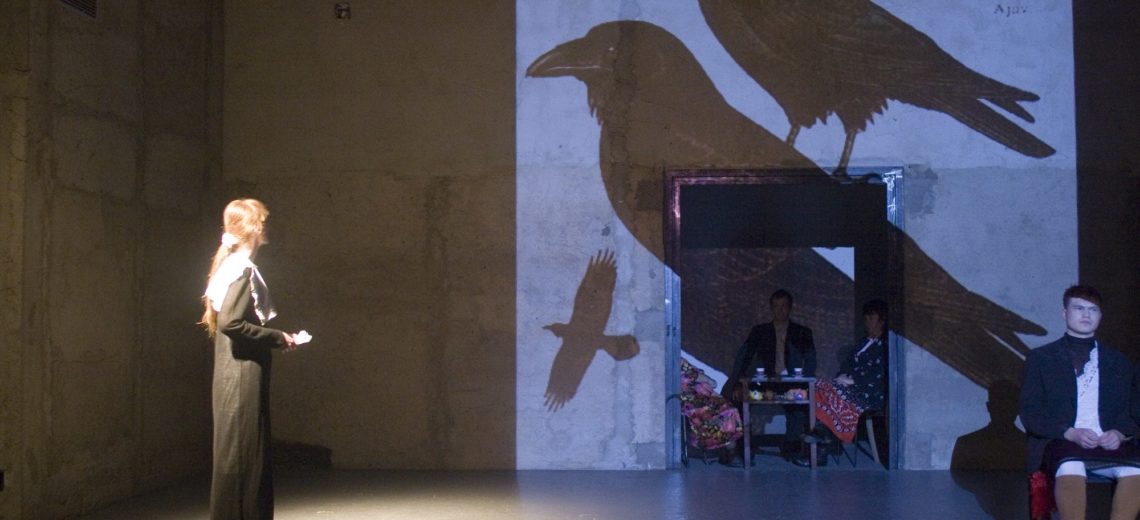 A subtle woman-girl on the scene watches a large-format projection of birds on the stage horizon