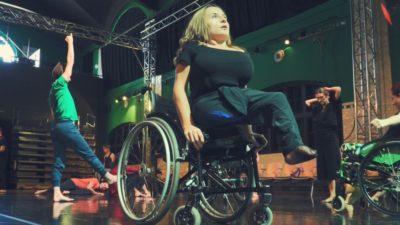 A female performer raises herself up from her wheelchair