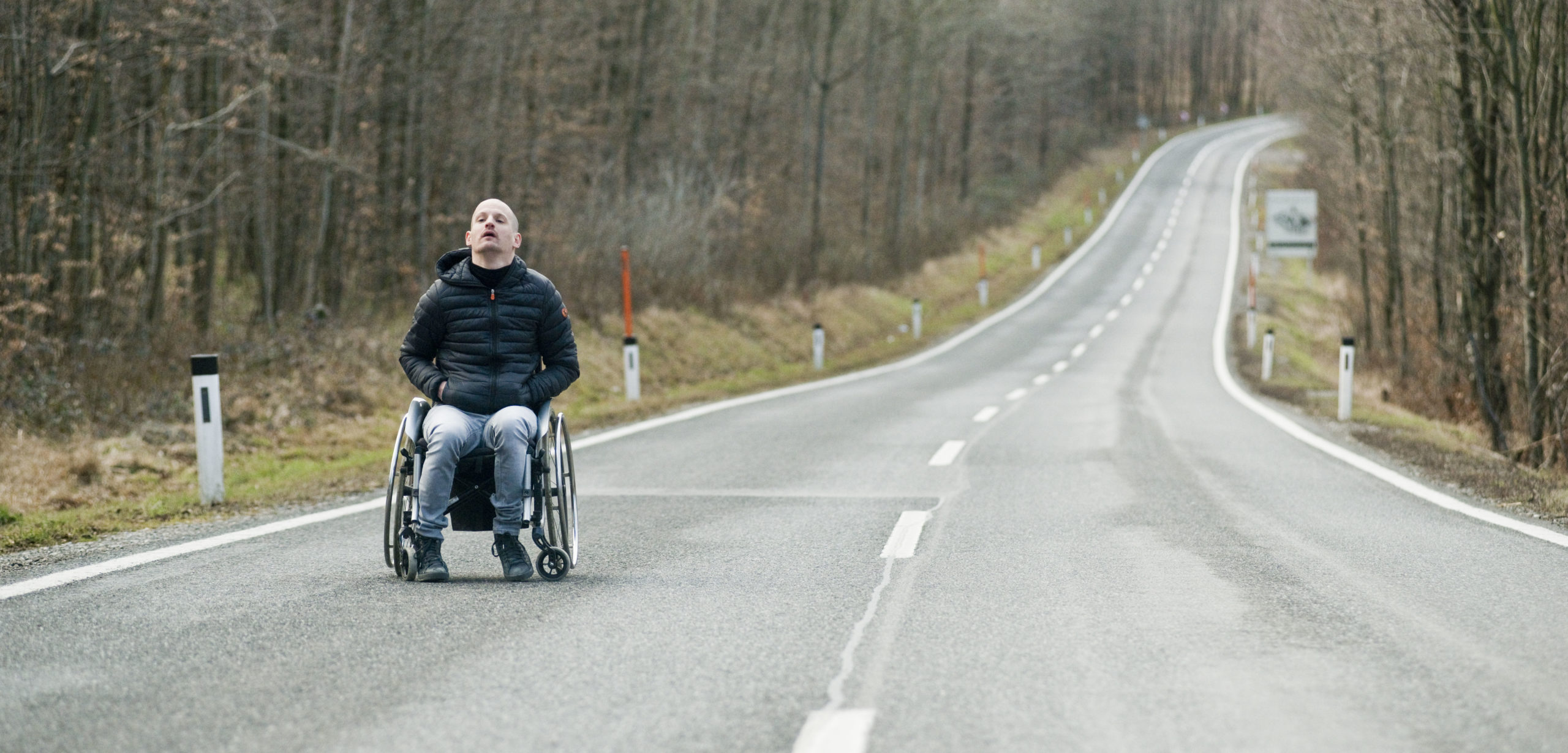 Man in wheelchair in the middle of an empty road
