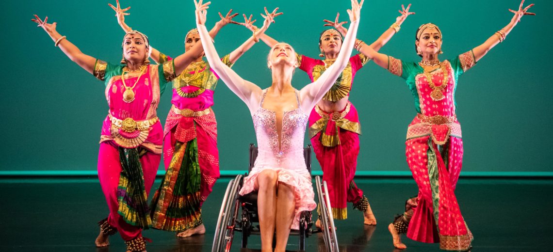 Female wheelchair dancer framed by 4 dancers on stage