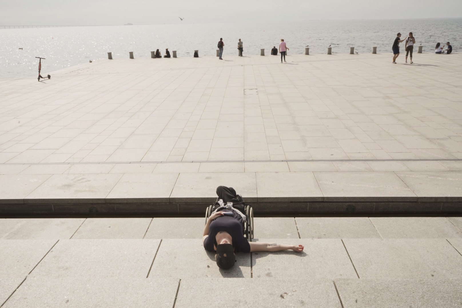 Wheelchair user lying on her back with a seaside scene in the background