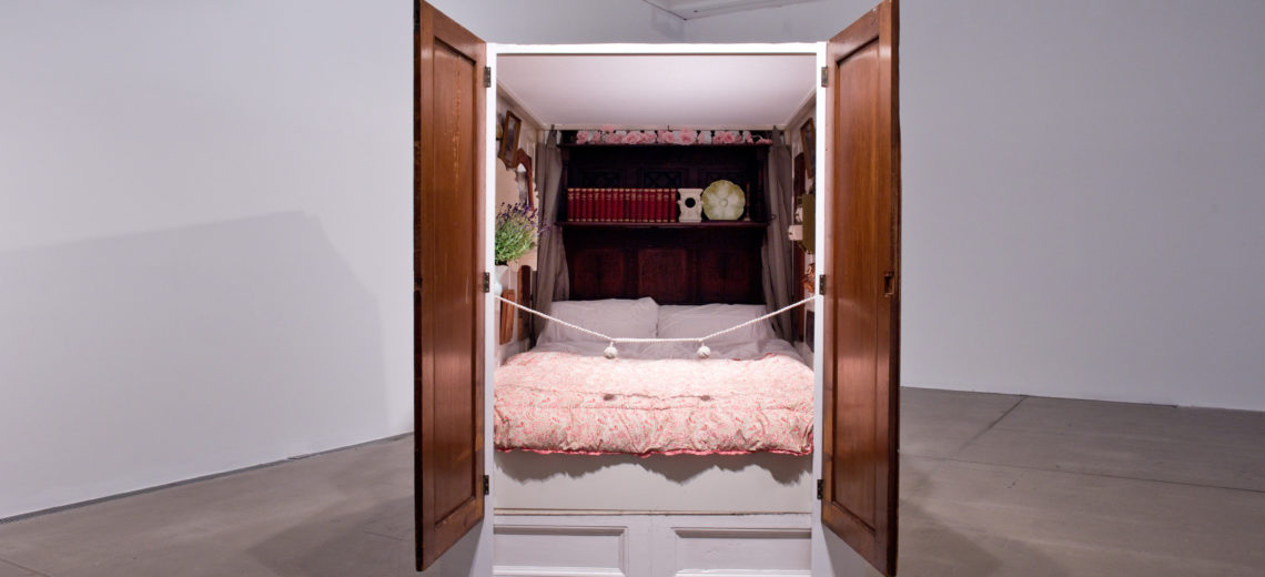 A bed entirely enclosed by panels, filled with old things