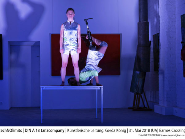 Two dancers, which look like cyborgs, on a table. A women and a man with a leg prosthesis.