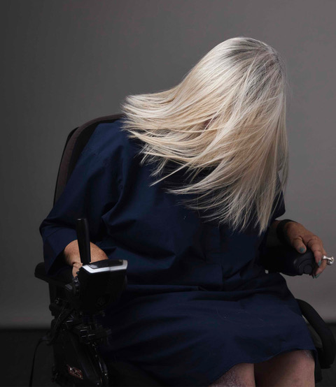 Female wheelchair user with flowing blonde hair swishes it so that it covers her face