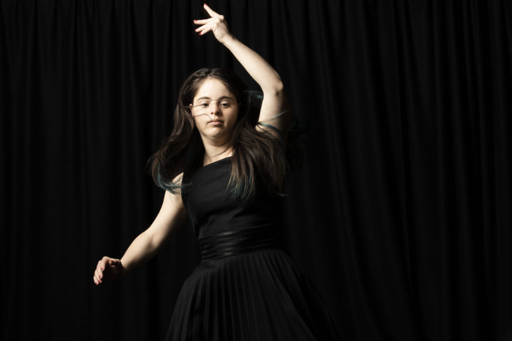 White learning disabled woman in a black dress dances expressively