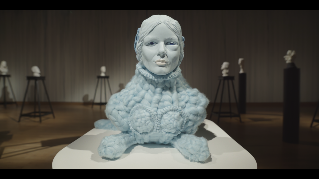 Photograph of a creature with lions body made of blue wool, it's head is realistic sculpture of a woman's head