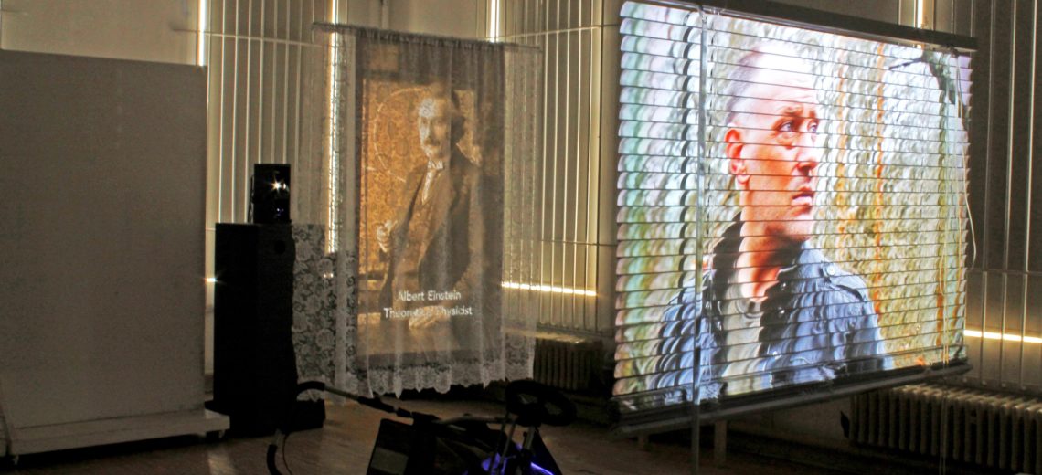 We see an everyday Venetian blind projected upon by a narrative video, the video shines through the blind, so that the video is on both sides of the blind.  In another part of the installation, we see a series of photographs projected of successful people who have experienced mental issues, covered in a window net. Beneath is an upturned child's buggy, which suggests we don't possibly know what a child will become in life.