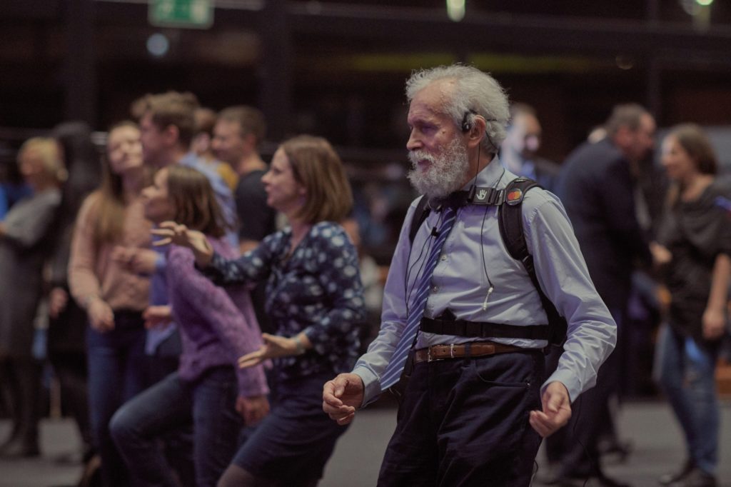 A man dancing and wearing a special set: a backpack and a headband vibrating to the beat of the music It is a set helping deaf people to feel music. 