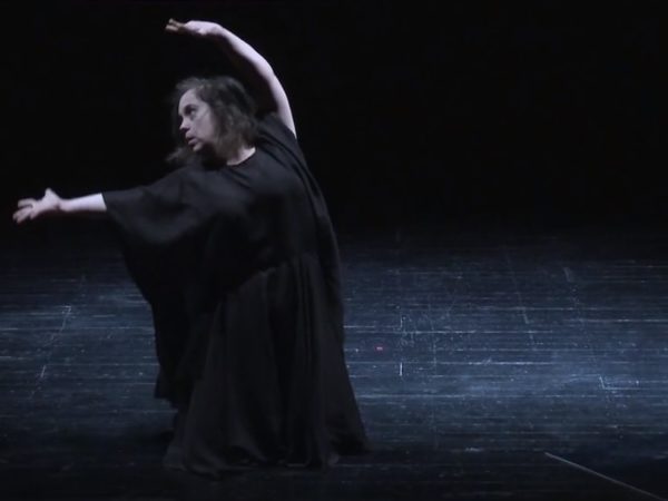 Learning disabled woman in a black outfit dancing expressively