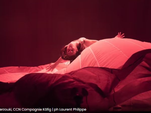 A female performer lays back on a billowing red fabric