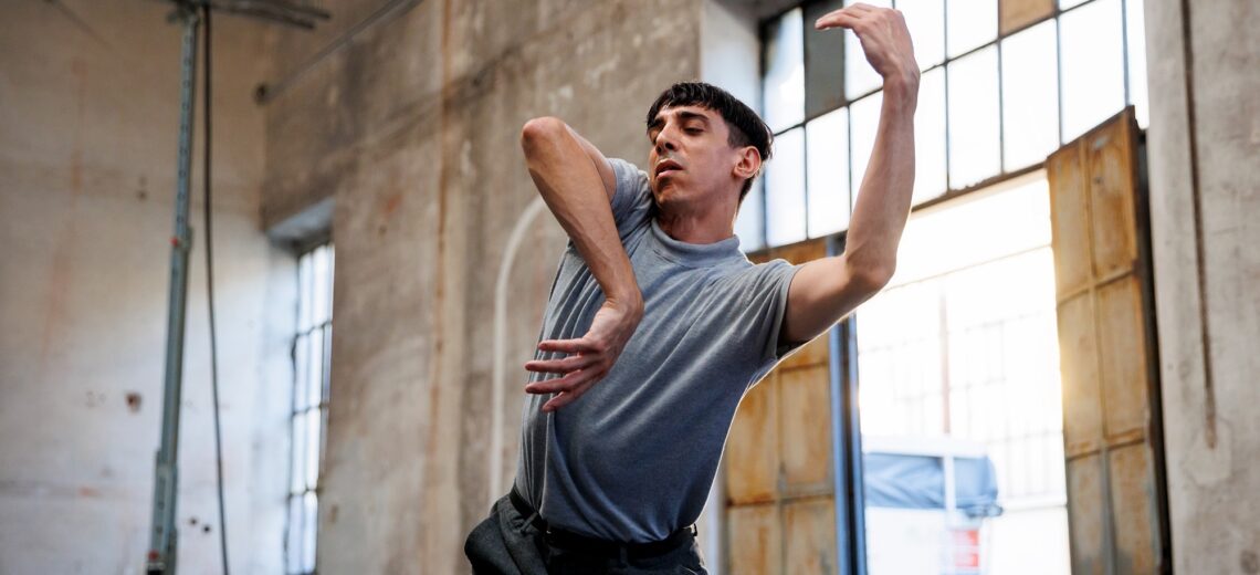A non-disabled dancer extends his elbows jauntily