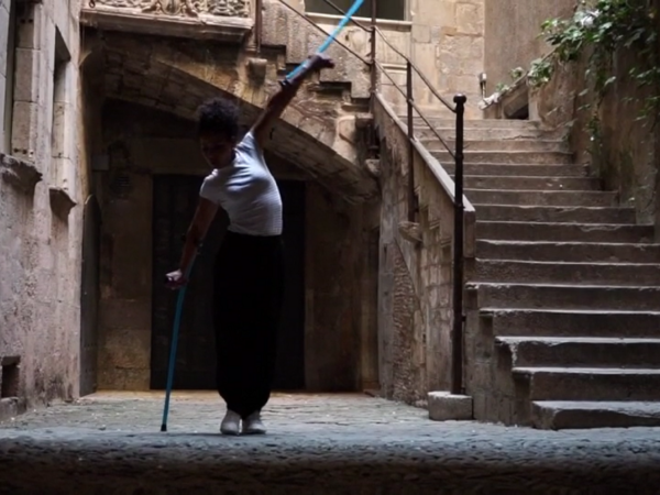 A female performer using crutches raises on high in the air amidst a historic courtyard