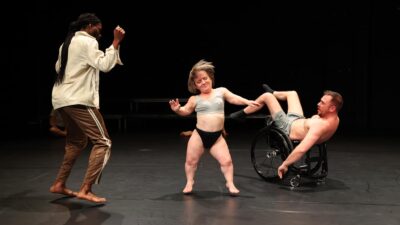 A small female performer jives energetically, her hair flying upwards as she moves