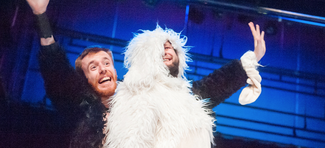 Pair of males wearing furry costumes and singing together on a stage